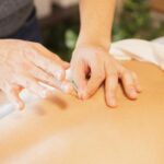 A practitioner inserting a fine acupuncture needle into a person's back during a treatment session.