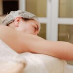 A woman receiving post-treatment acupuncture care, lying on a treatment table with acupuncture needles placed on her back and arm.