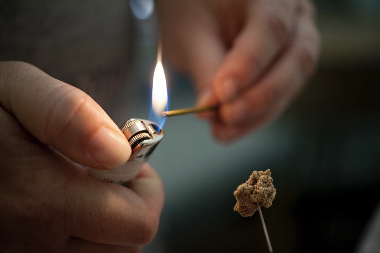 Moxibustion therapy at London Holistic Health Clinic, with a practitioner lighting a moxa stick over an acupuncture needle.
